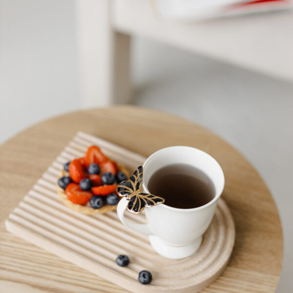 Porcelianinis puodelis su juodu drugeliu