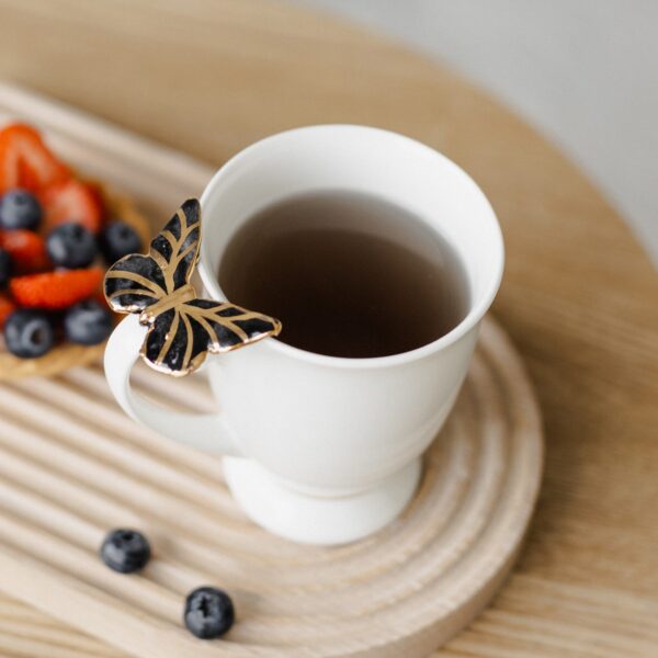 Porcelianinis puodelis su juodu drugeliu